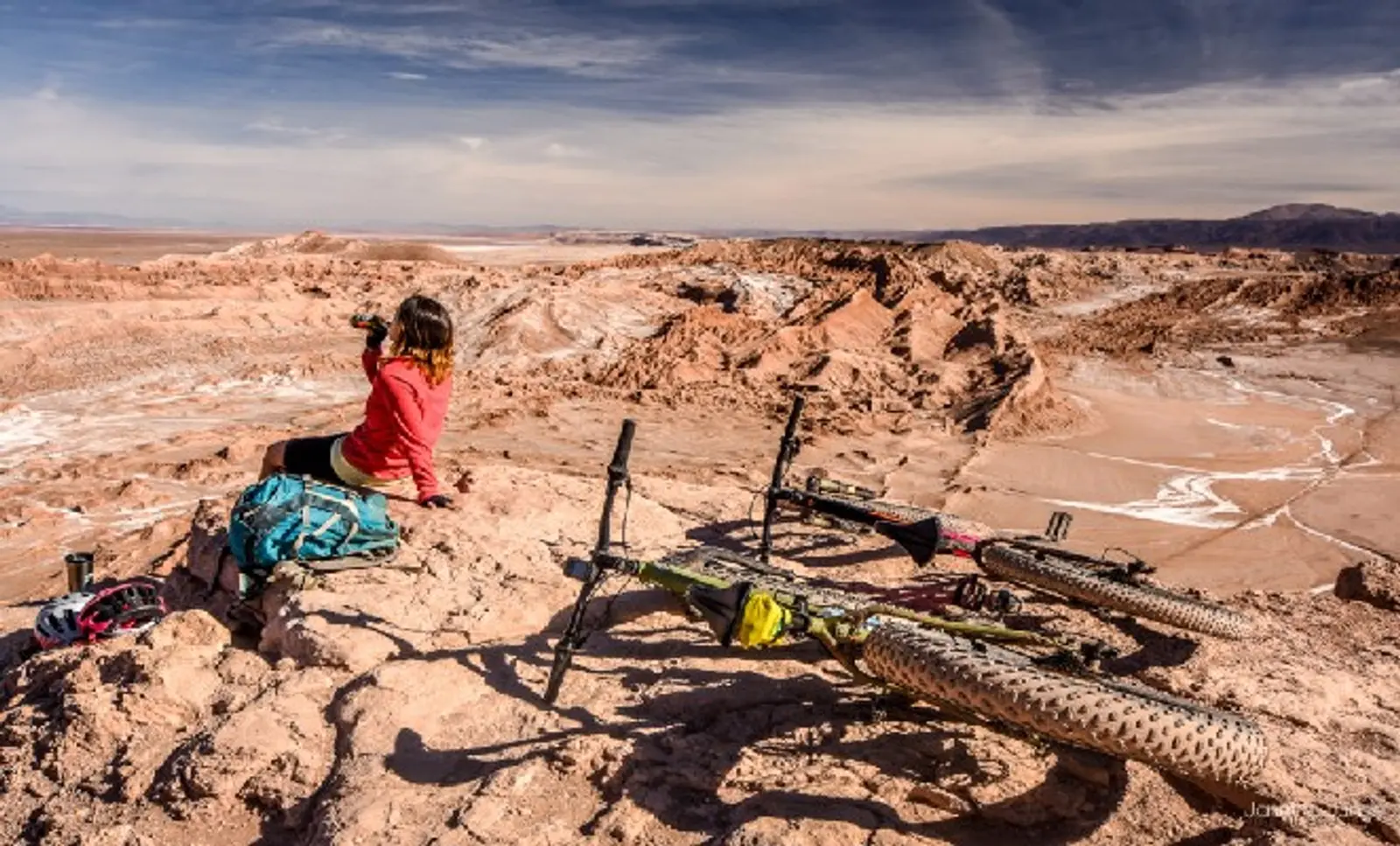 Viajante bebe água e descansa ao lado de sua bicicleta no Atacama