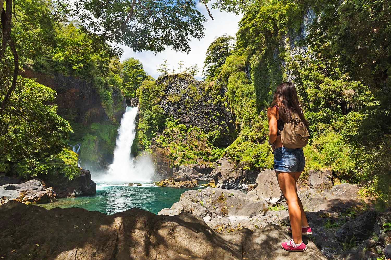 Mujer frente a cascada en el bosque