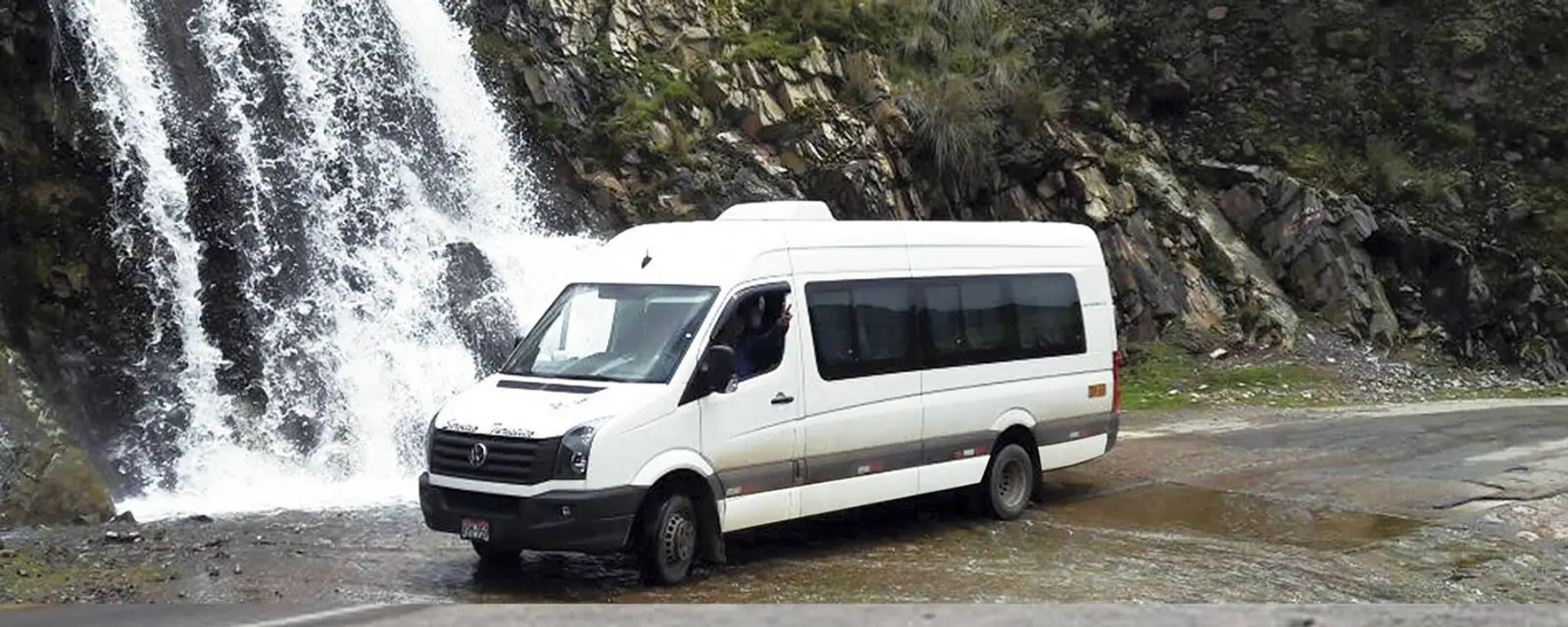 Minivan branca na frente da cachoeira