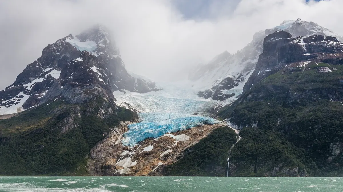 Glaciar entre montañas y frente a lago