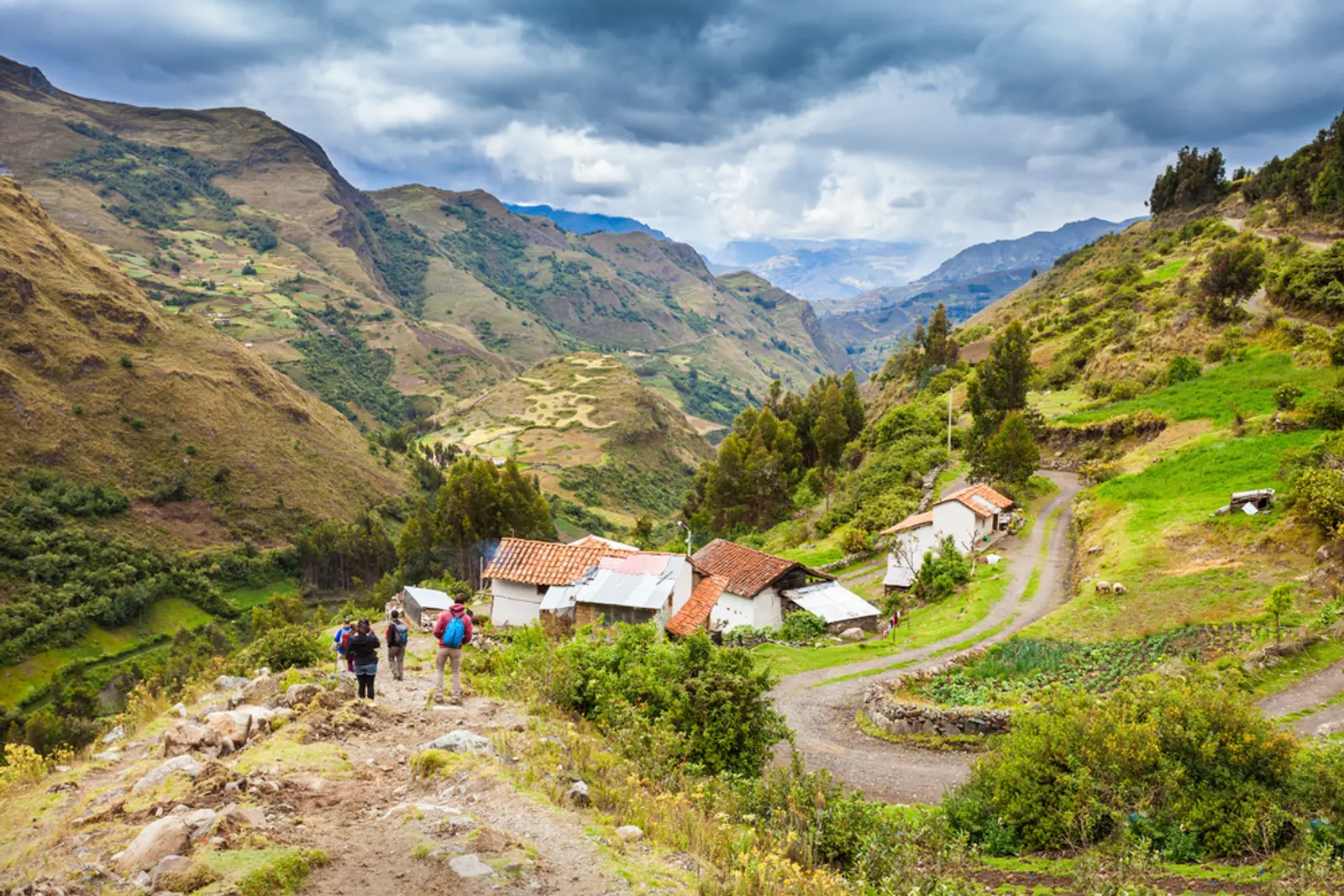 Viajeros caminan por paisaje agrícola en trekking santa cruz