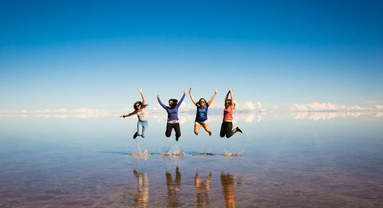 Jóvenes saltando en salar con efecto espejo