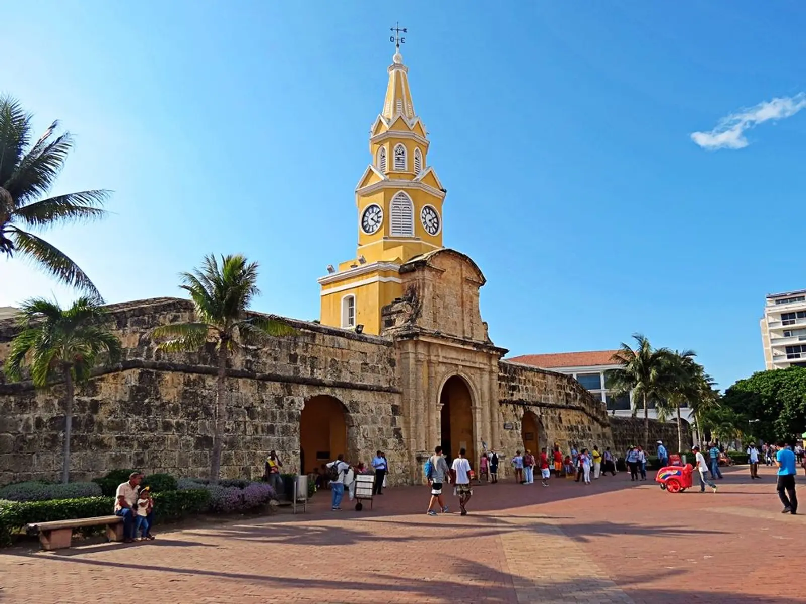 Personas caminando frente a torre del reloj en cartagena