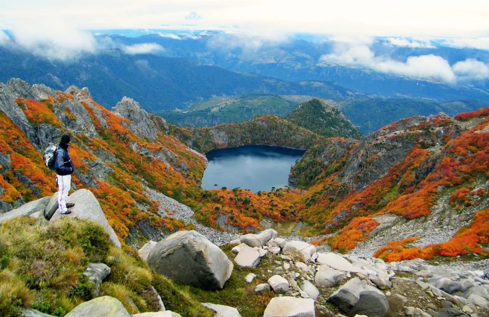 Viajero observando laguna desde una montaña