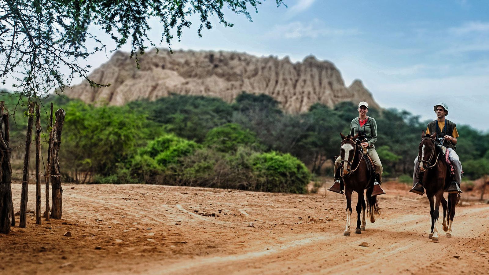 Dos personas cabalgando en medio de bosque en el desierto