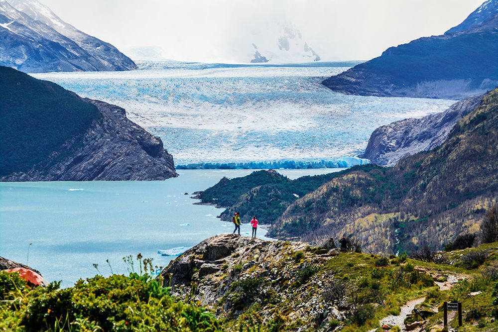 Glaciar de fondo entre las montañas y dos viajeros en torres del paine