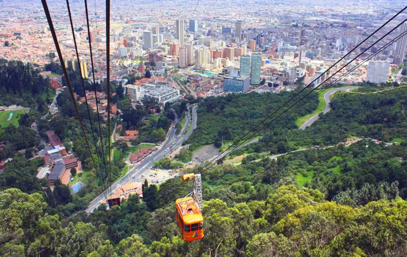 Teleférico en un cerro lleno de verde observando la ciudad de Bogotá