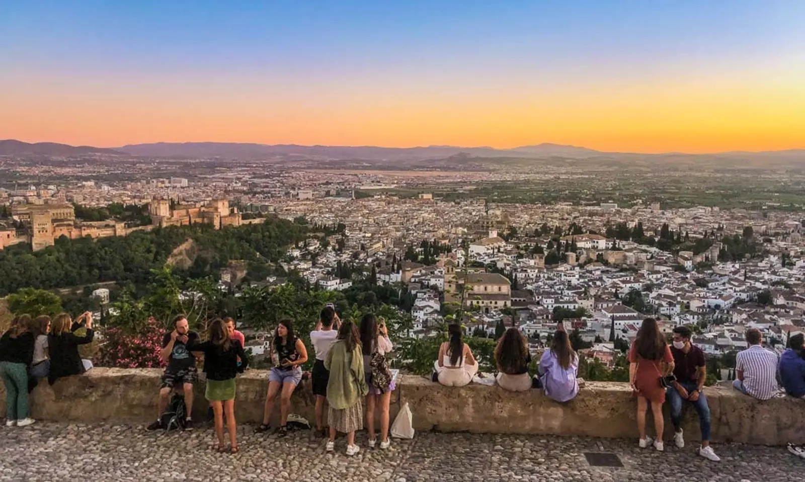 Personas observando ciudad de Granada al atardecer desde un mirador